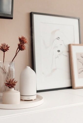 Aroma Diffuser auf Kommode mit Blumen Deko und Bildern