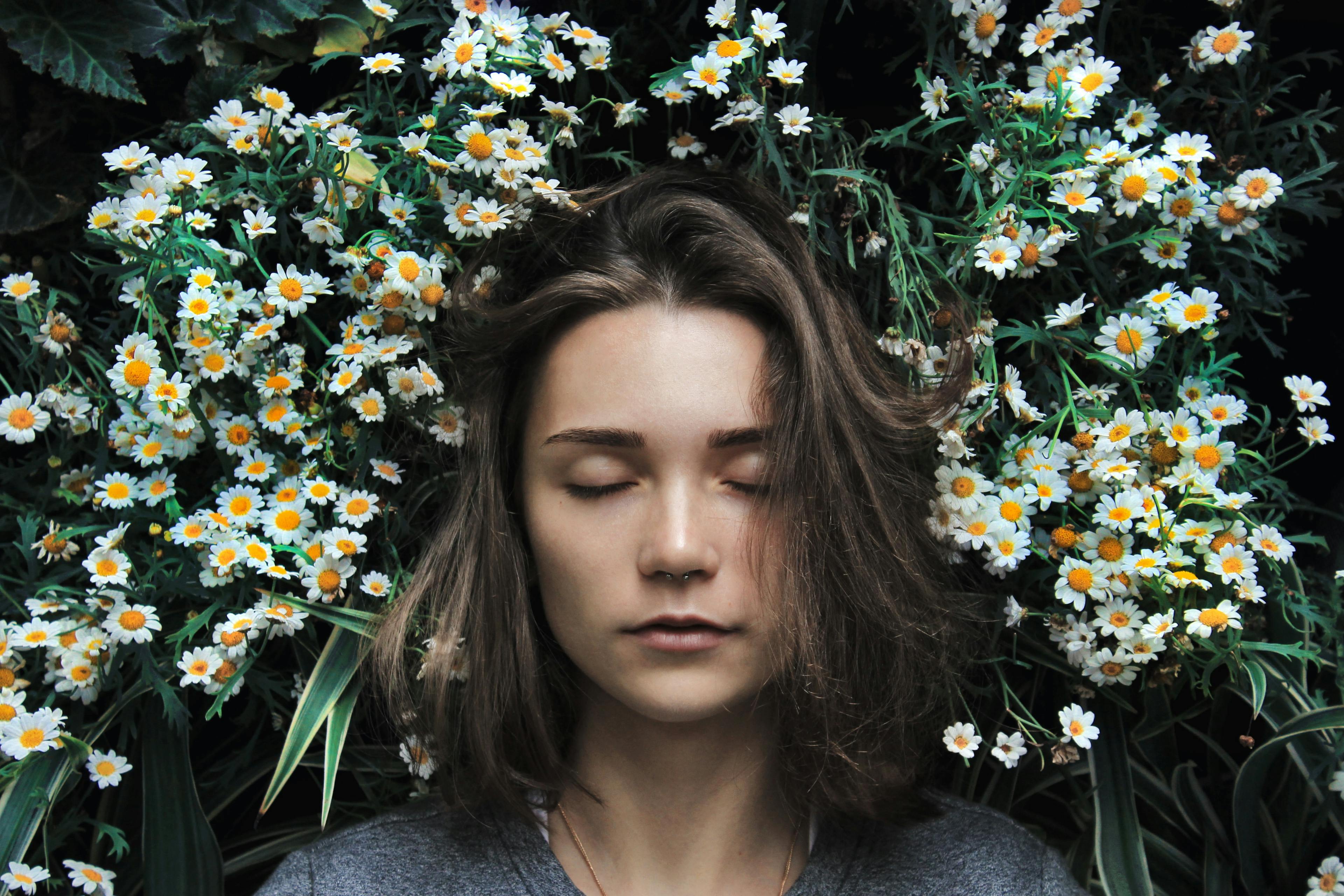 Frau mit geschlossenen Augen liegt in Blumen
